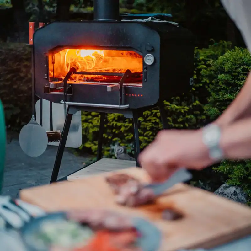 Vonken houtgestookte pizza oven in gebruik met op de voorgrond voorbereiding voor een heerlijke pizza