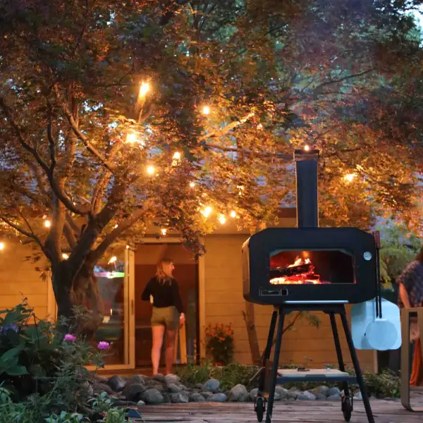 Sfeervolle houtgestookte pizza oven geplaatst in een verlichte tuin