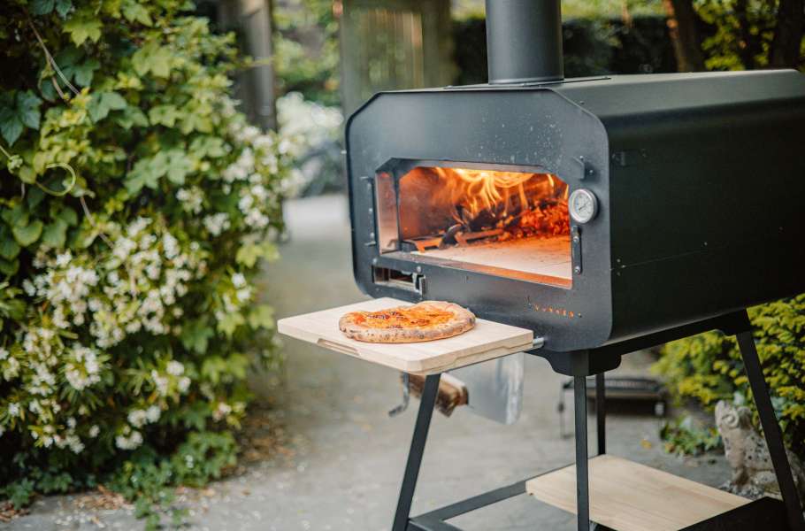 Houtgestookte pizza oven in een prachtige tuin, perfect voor buitenkoken.