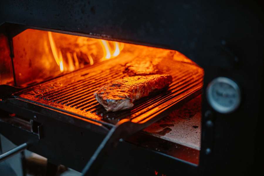 Houtgestookte pizza oven buiten met een heerlijk gebakken pizza maar ook voor steak