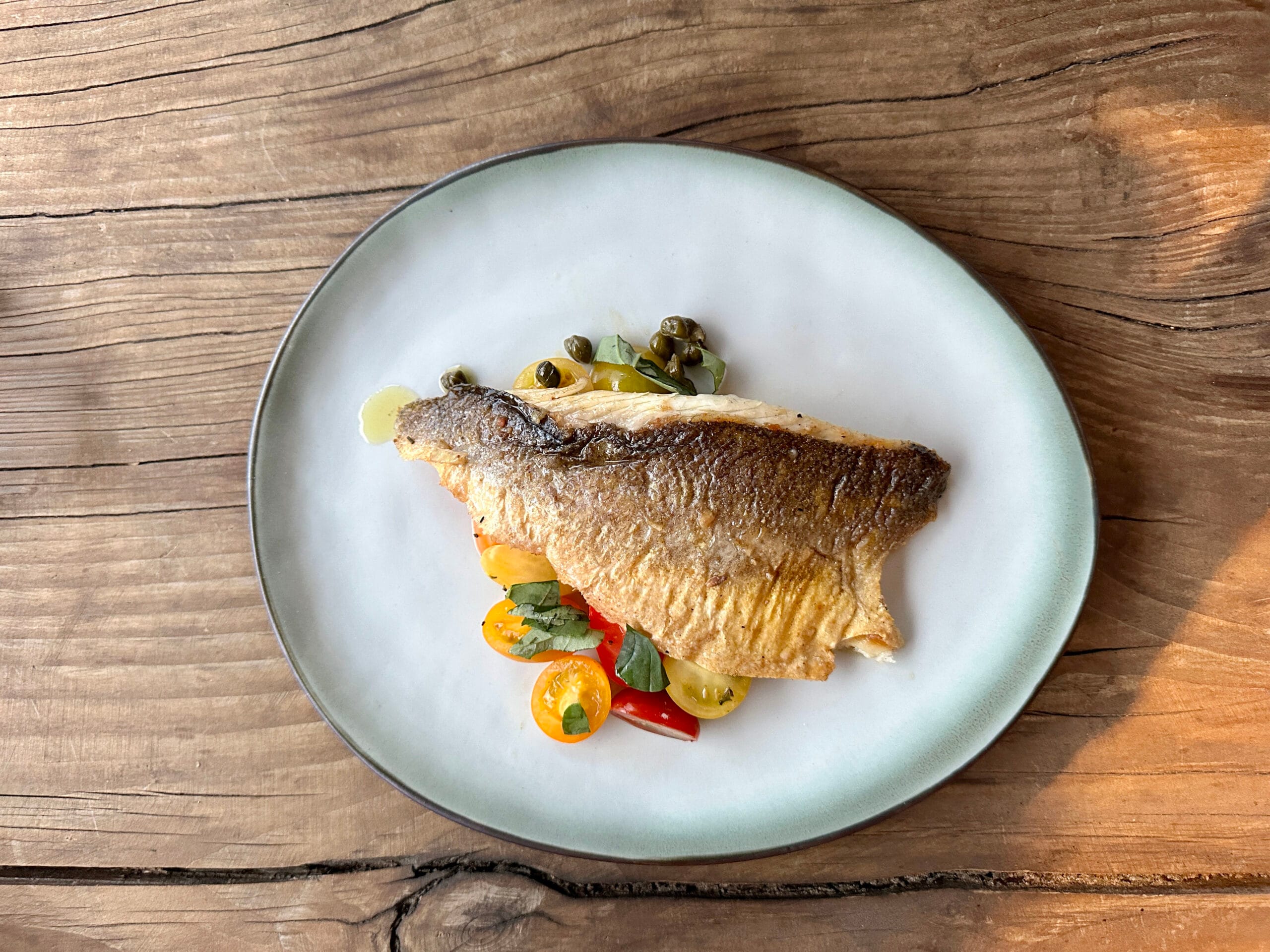Krokante zeebaars met lauwe tomaten, ansjovis en kappertjes