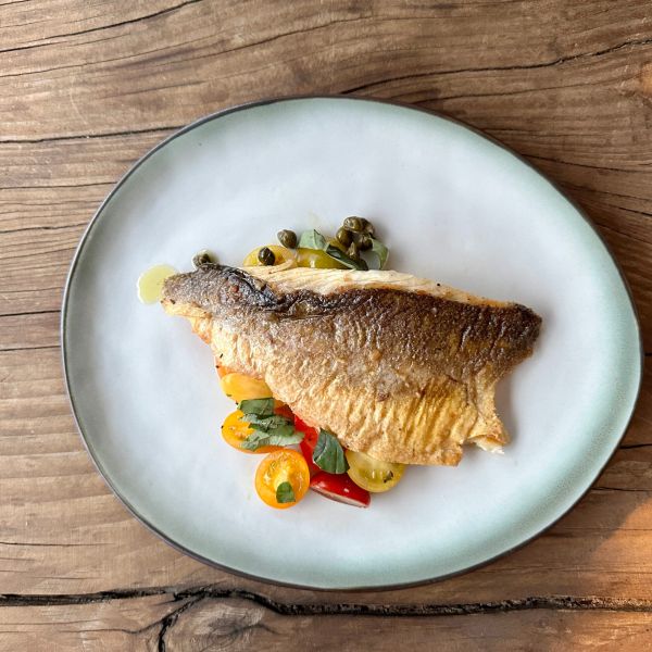 Krokante zeebaars met lauwe tomaten, ansjovis en kappertjes